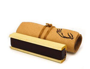 A rolled piece of brown paper tied with string and stamped with an antler design sits behind a rectangular ink stamp with a wooden handle on a white background.